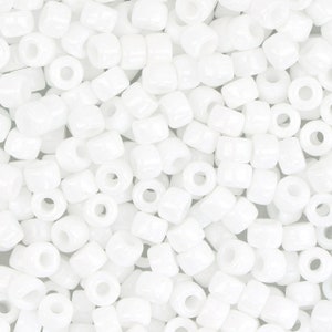 Op de afbeelding: Een close-up van een stapel witte ronde zaadkraaltjes. De kralen zijn ondoorzichtig en hebben een gladde, glanzende afwerking.