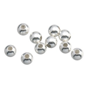 May include: A group of silver-toned round beads with a hole in the center. The beads are scattered on a white background.