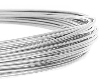 May include: Close-up of a coil of shiny, silver-colored wire. The wire is tightly wound, creating a dense, circular shape. The smooth, metallic surface reflects light, highlighting the individual strands and the overall texture.