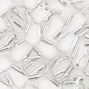 Op de afbeelding: Close-up van talrijke zilverkleurige krimpeindstukken, essentieel voor het maken van sieraden en knutselen. Deze kleine metalen componenten zijn ontworpen om de uiteinden van koorden of kettingen te bevestigen, wat een professionele afwerking geeft. Witte achtergrond.