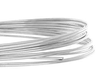 May include: Close-up of a coil of silver-colored wire. The wire is tightly wound, with multiple strands visible. The wire appears to be smooth and reflective, with a slight sheen. The background is plain white.