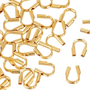 Op de afbeelding: Een stapel gouden metalen krimpkralen, gebruikt voor het maken van sieraden.