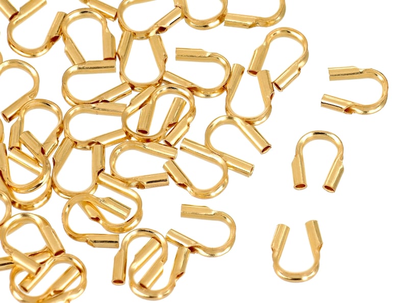 Op de afbeelding: Een stapel gouden metalen krimpkralen, gebruikt voor het maken van sieraden.