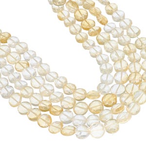 May include: Close-up of multiple strands of faceted, round gemstones in shades of yellow and clear. The beads are strung together, creating a layered effect. The gemstones have a polished, reflective surface, and are set against a white background.