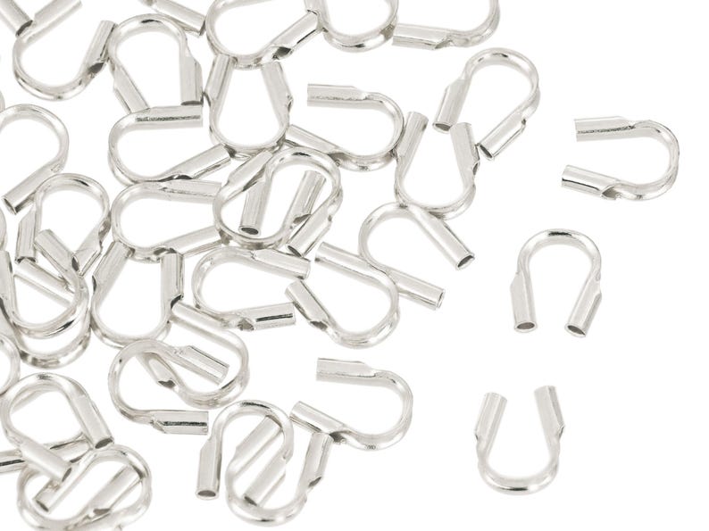 Op de afbeelding: Een verzameling zilverkleurige, metalen S-vormige krimpaansluitingen, gebruikt voor het maken van sieraden en ambachten. De connectoren hebben een lus aan &eacute;&eacute;n uiteinde en een krimpkoker aan het andere.