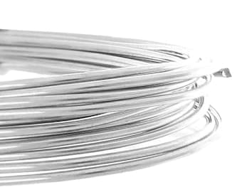 May include: Close-up of a coil of shiny, silver-colored wire. The wire is tightly wound, creating a circular shape. The bright metal reflects light, highlighting the smooth texture of the wire. The background is plain white.