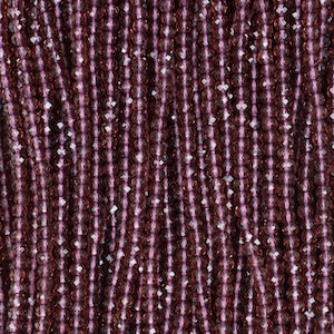 May include: Close-up of strands of faceted beads in shades of burgundy and light purple. The beads are strung together, creating a textured surface. The beads are small and round, with multiple facets that catch the light.