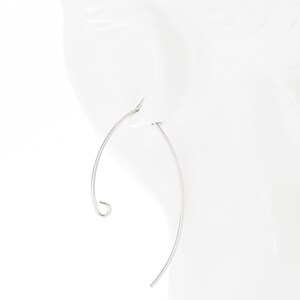 May include: A pair of silver hoop earrings with a curved design. The earrings are thin and delicate.