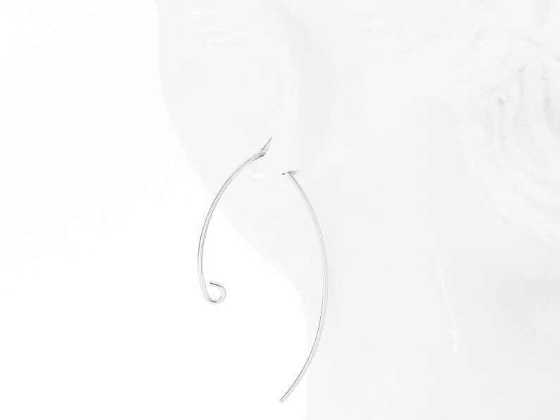 May include: A pair of silver hoop earrings with a curved design. The earrings are thin and delicate.