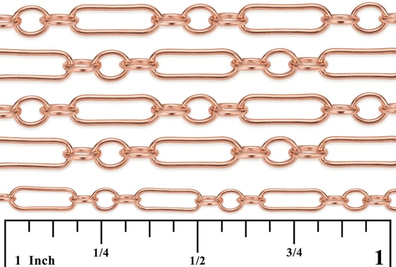 May include: Close-up of a rose gold chain with oval and round links. The chain is shown against a white background with a ruler for scale. The ruler shows measurements in inches.