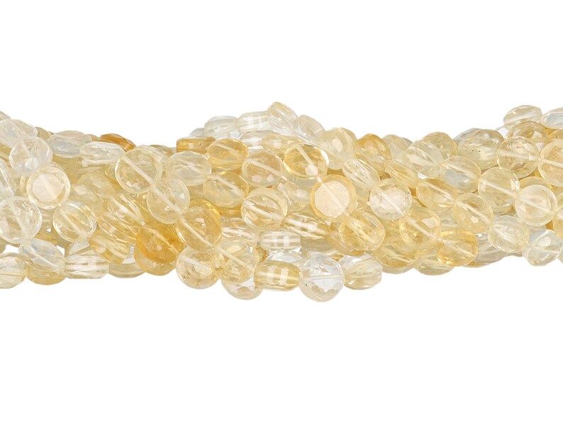 May include: A strand of light yellow citrine gemstone beads. The beads are oval-shaped and faceted, with a translucent appearance. The color varies from pale yellow to a deeper golden hue.