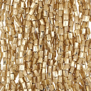 May include: A close-up of a strand of gold-colored square beads. The beads are arranged in a vertical pattern, creating a shimmering effect.