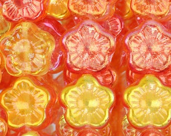 May include: A close-up of a pile of orange and yellow glass flower beads. The beads are iridescent and have a shiny finish.