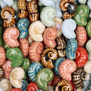 以下が含まれることがあります： 青、緑、ピンク、茶色、白など、さまざまな色のセラミック製の貝殻の置物のコレクション。 螺旋状の貝殻が密集して配置され、質感のある装飾的な模様を作り出しています。