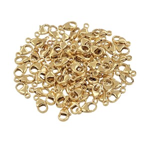 May include: A large pile of gold-toned lobster clasps, a type of jewelry finding used for making necklaces, bracelets, and other jewelry.