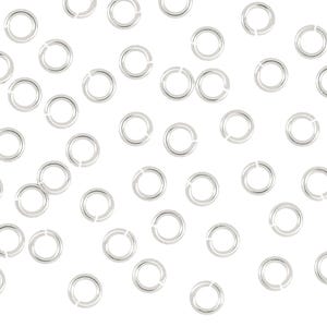 May include: A large quantity of silver jump rings, a type of jewelry finding, scattered on a white background.