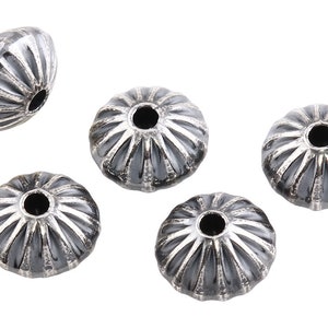 May include: Five silver-toned metal beads with a textured, ridged design. The beads have a hole in the center for stringing.