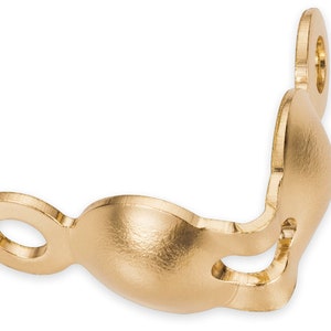May include: A gold-colored, decorative metal bracket with a curved design. It features two circular openings and a rounded, bulbous shape in the center. The bracket is likely used for decorative or functional purposes.