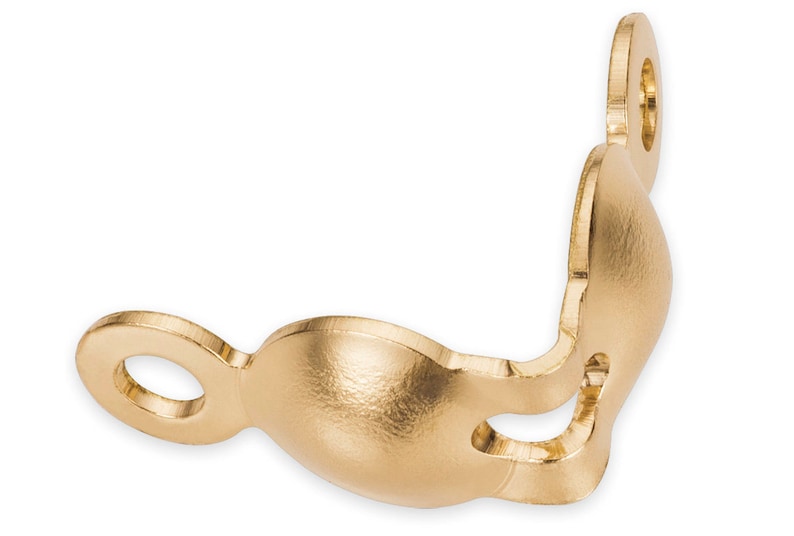 May include: A gold-colored, decorative metal bracket with a curved design. It features two circular openings and a rounded, bulbous shape in the center. The bracket is likely used for decorative or functional purposes.