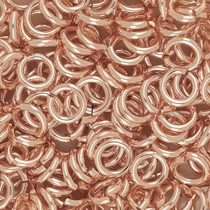 Puede incluir: Una imagen de primer plano de una gran pila de anillos de salto de oro rosa. Los anillos de salto son todos del mismo tama&ntilde;o y est&aacute;n dispuestos en un patr&oacute;n aleatorio.