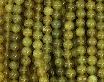 May include: A close-up of a strand of round, yellow-green jade beads. The beads are smooth and polished, with a slight translucence.