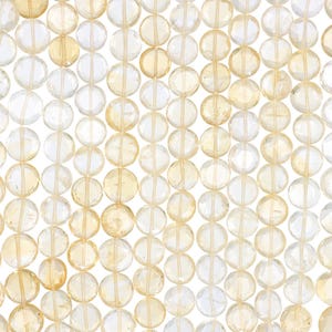 May include: Close-up of a collection of faceted, round beads in shades of yellow and clear. The beads are strung together, creating a pattern of light and color. The beads are likely gemstones, perfect for jewelry making.