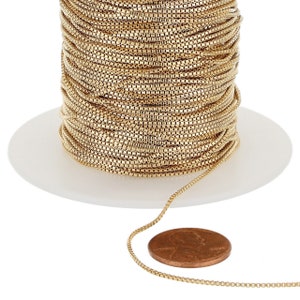 Puede incluir: Un carrete de cadena de color dorado, con un tramo de cadena que se extiende desde el carrete. Un céntimo de euro se coloca junto a la cadena para la escala.