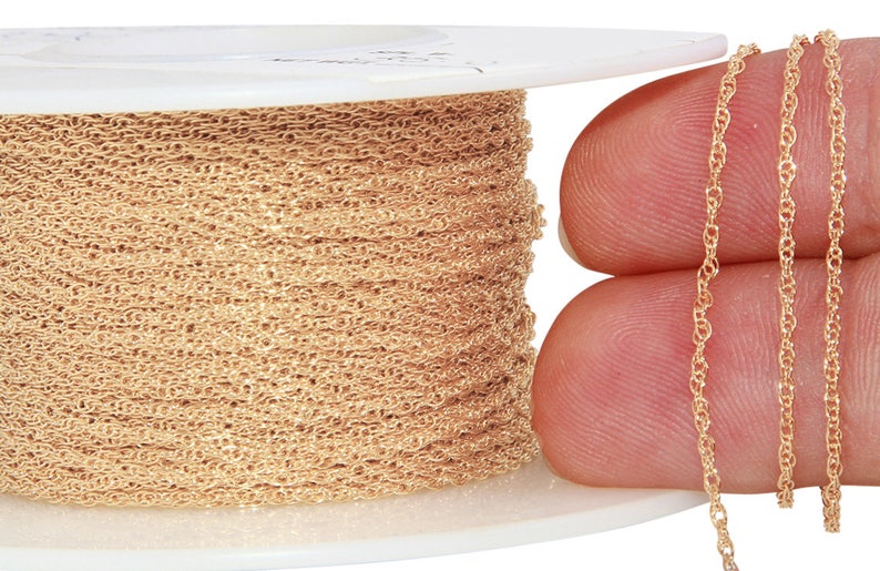 May include: A spool of gold-colored chain, with a close-up of the chain itself. The chain is delicate and has a slightly twisted design.