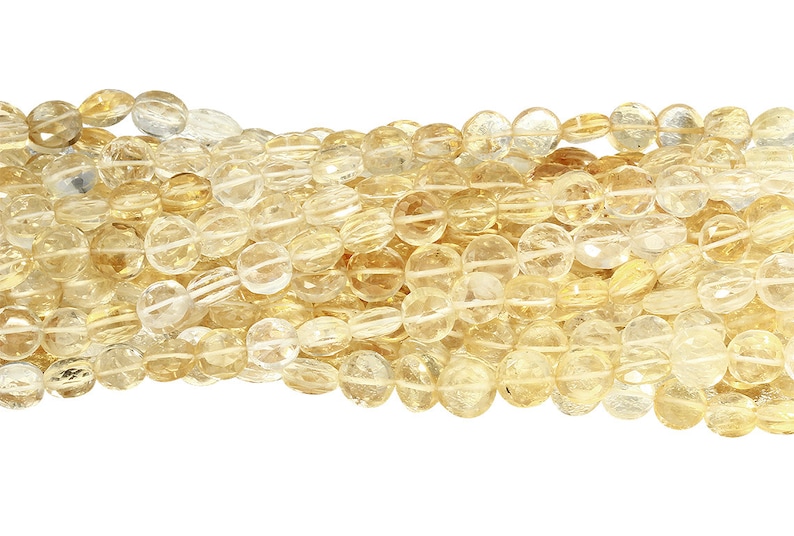 May include: Strands of polished, oval-shaped citrine gemstone beads. The beads are a translucent yellow-orange color, with a faceted surface. The beads are strung together, creating a flowing, textured appearance. Ideal for jewelry making.