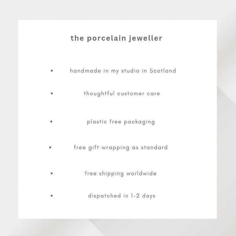 May include: A white informational card with dark gray text titled the porcelain jeweller. The list includes: handmade in my studio in Scotland, thoughtful customer care, plastic free packaging, free gift wrapping as standard, free shipping worldwide, and dispatched in 1-2 days.