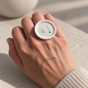May include: A white circular ring featuring a raised edge and a flat center surface. The center displays the black text "I'm not done" positioned to the left of a thin vertical black line that terminates in a small black dot at the bottom.