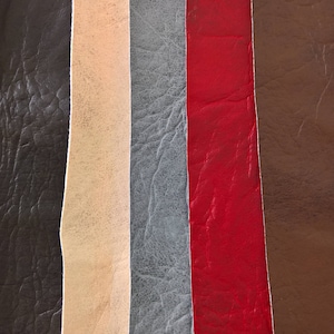 May include: A close-up of seven different leather swatches in various colours, including black, brown, beige, grey, red, and dark brown. The swatches are arranged vertically and show the texture of the leather.