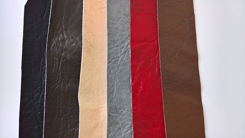 May include: A close-up of seven different leather swatches in various colours, including black, brown, beige, grey, red, and dark brown. The swatches are arranged vertically and show the texture of the leather.