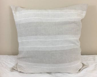 May include: A white and gray striped pillow with a linen texture. The pillow is square and has a simple design.