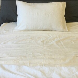 May include: A white linen bed sheet with a white linen pillow on top. The sheet is smooth and wrinkle-free.
