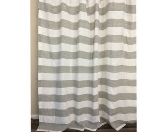 Puede incluir: Un par de cortinas de lino a rayas blancas y grises. Las cortinas están hechas de una tela suave y natural y tienen un aspecto relajado y casual.