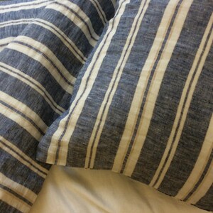 Pu&ograve; includere: Due federe a righe blu e bianche. Le federe sono realizzate in tessuto di lino e hanno una texture sottile.