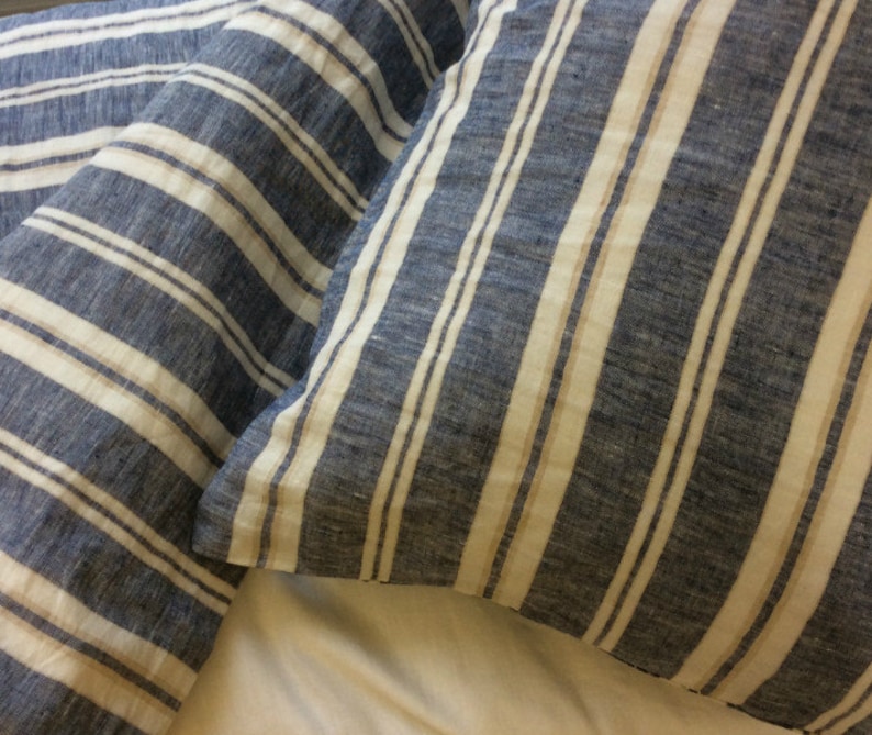 Pu&ograve; includere: Due federe a righe blu e bianche. Le federe sono realizzate in tessuto di lino e hanno una texture sottile.
