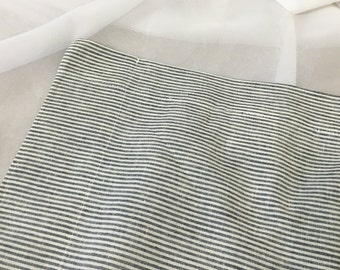 Puede incluir: Primer plano de una tela de rayas blancas y negras con un brillo sutil. La tela tiene una textura tejida y probablemente se utiliza para cortinas o tapicería.