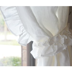 Puede incluir: Cortinas blancas de lino transparente con un ribete de volantes. Las cortinas est&aacute;n reunidas en la parte superior y atadas con una cinta.