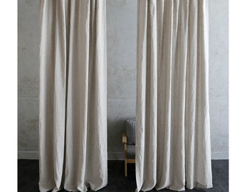 May include: Two pairs of off-white linen curtains hanging in a room with a grey wall and a wooden chair. The curtains are made of a natural fabric with a subtle texture.
