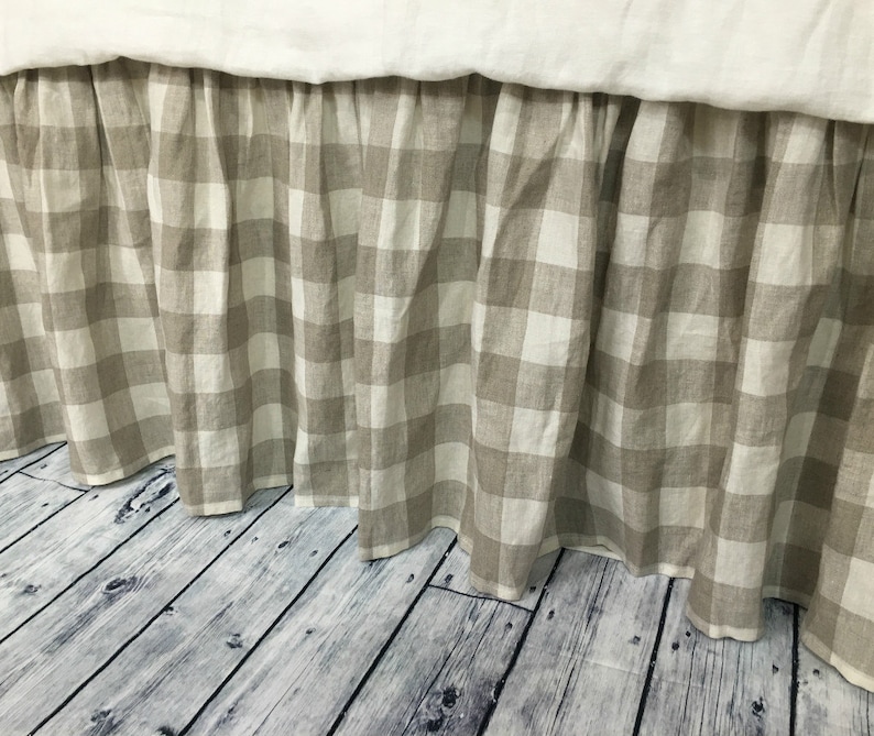 Pu&ograve; includere: Una gonna da letto in lino gingham beige e bianco con un bordo arricciato. La gonna &egrave; in lino e ha uno stile rustico informale.