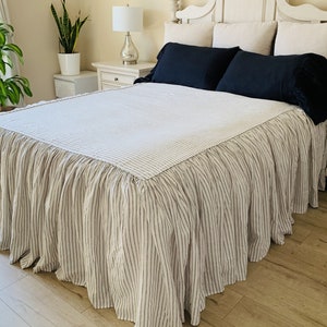 May include: White and black striped bed skirt with a ruffled edge. The skirt is made of linen and has a relaxed, casual look.