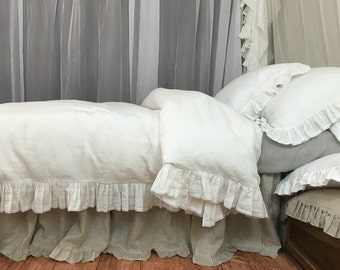 May include: White linen bedding with a ruffled edge and a matching linen bed skirt. The bedding is on a bed with white sheer curtains in the background.