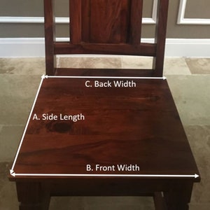May include: A dark brown wooden chair with a rectangular seat and a slatted back. The seat has a trapezoidal shape. The chair is made of solid wood and has a rich, warm tone. The chair is designed for seating.