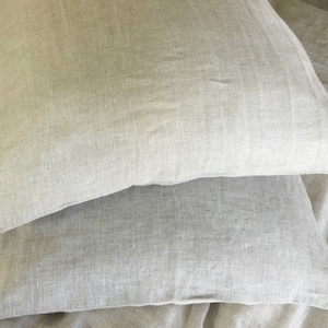 May include: Two light gray linen pillowcases stacked on top of each other. The pillowcases are made of a soft, natural fabric and have a subtle herringbone pattern.