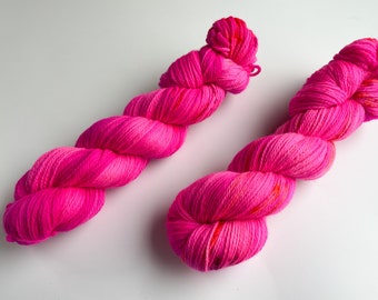 Hand dyed superwash Merino DK weight yarn. Fluoriscent pink with some orange and red speckles.