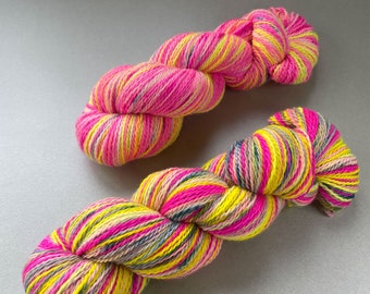 Handgeverfd, zelfstrepend Polwarth en Tussah zijden sokkengaren. Fluorescerend roze, geel en spikkels.