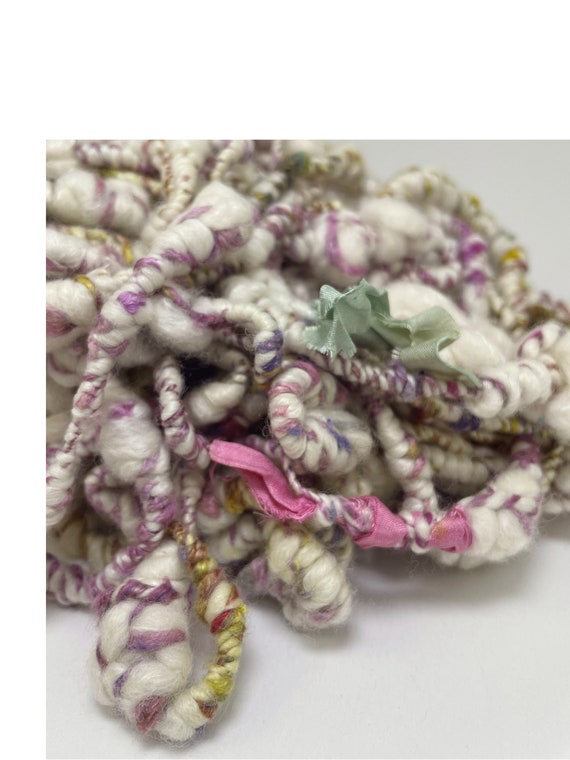 Hand spun art yarn. Chunky supercoils in white with a colorful silk accent.