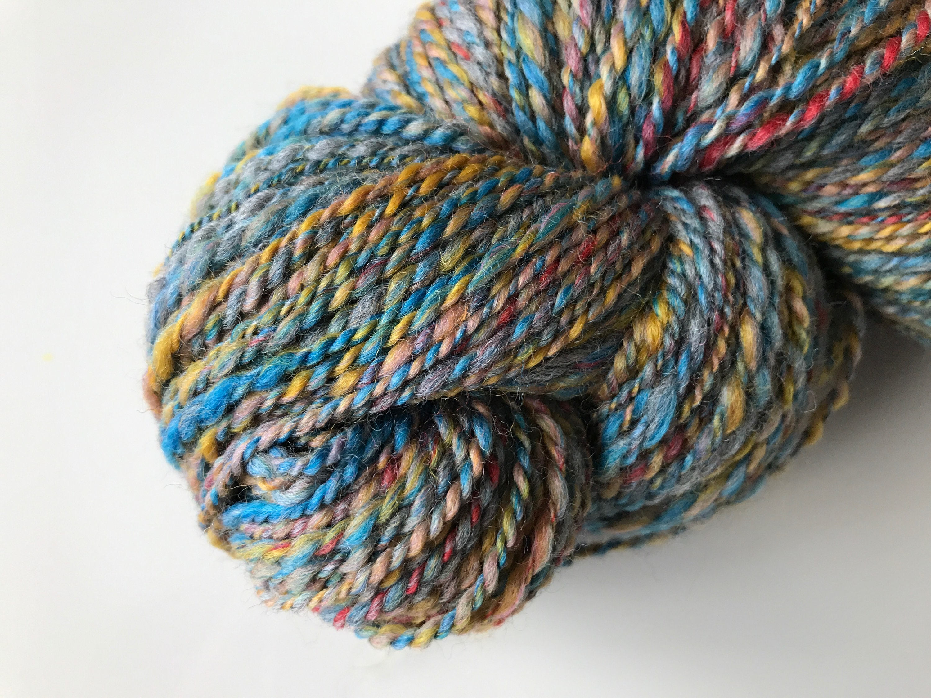 Sportweight hand spun yarn with BFL and Merino wool mix in blue, red, yellow and grey.